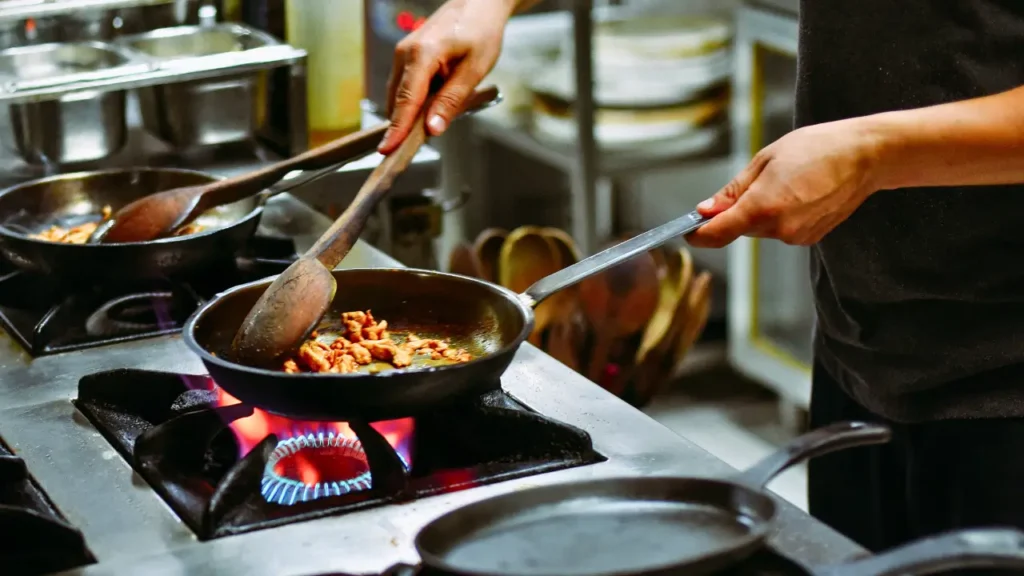 Pessoa cozinhando com gás de cozinha em restaurante.